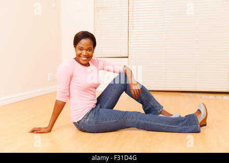 attraktive junge afrikanische Frau sitzen auf Holzboden in ihr erstes neues Haus Stockfoto