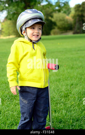 Ein kleiner Junge mit seinem Roller im Park zu spielen. Stockfoto