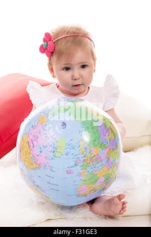 Babymädchen Welt Ball halten und sitzen auf flauschige Decke Stockfoto
