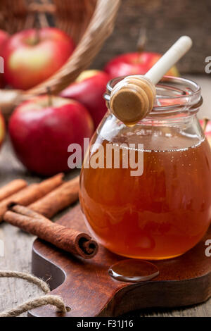 Honig-Löffel, Glas Honig, Äpfeln und Zimt auf einem hölzernen Hintergrund Stockfoto