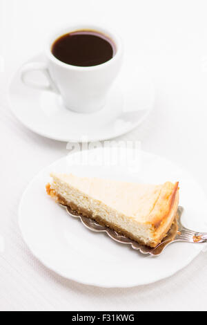 Frühstück-Restaurant-Menü-Hintergrund. Keil Käsekuchen auf den Spachtel und eine Tasse Kaffee auf weißen Tisch Stockfoto