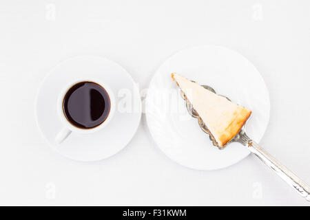 Frühstück-Restaurant-Menü-Hintergrund. Keil Käsekuchen auf den Spachtel und eine Tasse Kaffee auf weißen Tisch. Top View-Bild Stockfoto