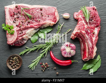 Rohes Rindfleisch Steaks mit Gewürzen auf dem schwarzen Schneidebrett. Stockfoto