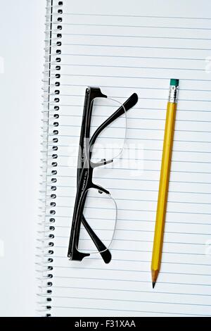 Spiralbindung Notebook gelbe Bleistift Radiergummi Brille Stockfoto