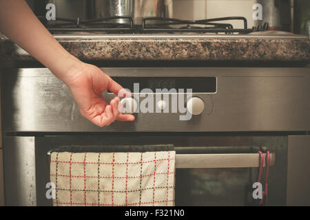 Die Hand einer jungen Frau dreht den Knopf auf dem Herd Stockfoto