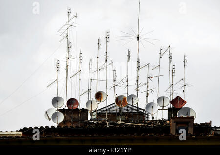 Mehrfache Satellitenschüsseln und Fernsehantennen auf einem Mehrfamilienhaus. Stockfoto