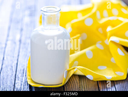 frische Milch in der Flasche und auf einem Tisch Stockfoto