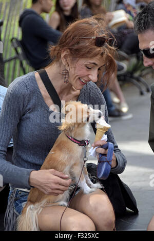 Eine attraktive Frau teilt ihr Eis mit ihrem Hund im Washington Square Park in New York City. Stockfoto