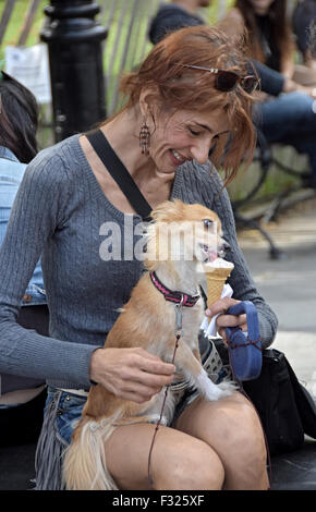 Eine attraktive Frau teilt ihr Eis mit ihrem Hund im Washington Square Park in New York City. Stockfoto