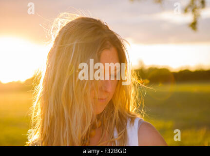 Eine starke Hintergrundbeleuchtung Porträt einer Frau (Alter 25-30) in einem Feld an einem Sommerabend Stockfoto