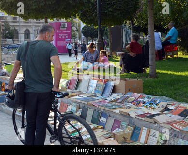 Ein Radfahrer hält um Bücher auf dem Bürgersteig am Piata Universitatii (Universitätsplatz) im Zentrum von Bukarest zu betrachten. Stockfoto