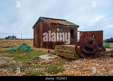 Verlassene rostenden Hütte links zu verrotten und zerfallen am Strand von Dungeness, Kent. Ein grauer, Stimmungsvoller Himmel verleiht die traurige Szene Stockfoto