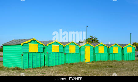 Badehäuschen UK. Grüne und gelbe Strand Hütten an einem sonnigen Tag mit blauem Himmel in Littlehampton, West Sussex, England, UK. Stockfoto