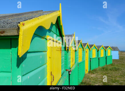 Badehäuschen UK. Reihe von grünen und gelben Strand Hütten an einem sonnigen Tag mit blauem Himmel in Littlehampton, West Sussex, England, UK. Stockfoto