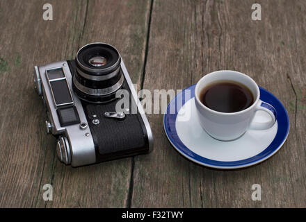 die alte Kamera und eine Tasse Kaffee auf einem Holztisch Stockfoto
