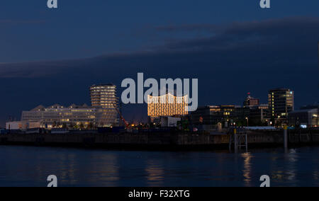 Hamburg, Deutschland. 28. Sep, 2015. Die beleuchtete Glasfassade des Elbphilharmonie wird neben dem Marco Polo Tower bei Sonnenaufgang in Hamburg, Deutschland, 28. September 2015 gesehen. Der Konzertsaal wurde von den Architekten Herzog & de Meuron entworfen und wird voraussichtlich am 11. Januar 2017 eröffnet. Foto: Christian Charisius/Dpa/Alamy Live News Stockfoto