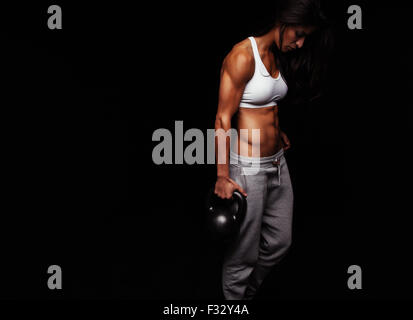 Muskulöse Frau Crossfit Übung zu tun. Harten Fitness weibliches Modell mit Wasserkocher Glocke auf schwarzem Hintergrund. Stockfoto