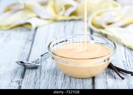 Vanillesauce in einer kleinen Schüssel (Nahaufnahme) auf hölzernen Hintergrund Stockfoto