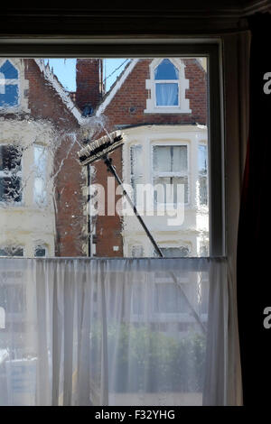 eine Fenster-Reiniger Bürste fegt über die Glasscheibe aus dem Inneren des Raumes gesehen Stockfoto