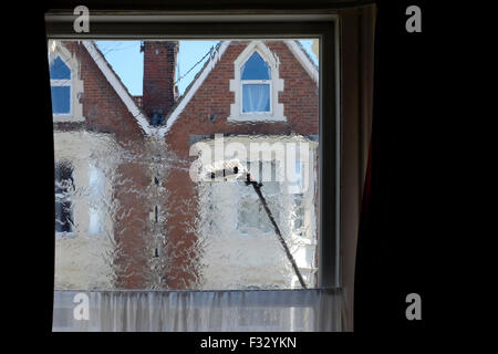 eine Fenster-Reiniger Bürste fegt über die Glasscheibe aus dem Inneren des Raumes gesehen Stockfoto