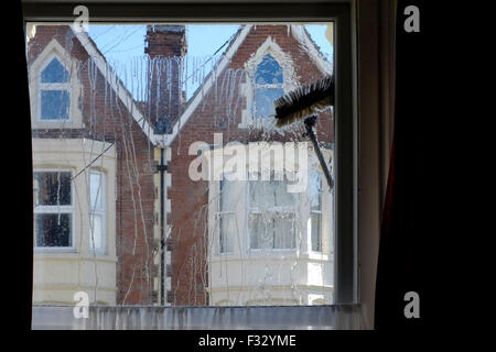 eine Fenster-Reiniger Bürste fegt über die Glasscheibe aus dem Inneren des Raumes gesehen Stockfoto