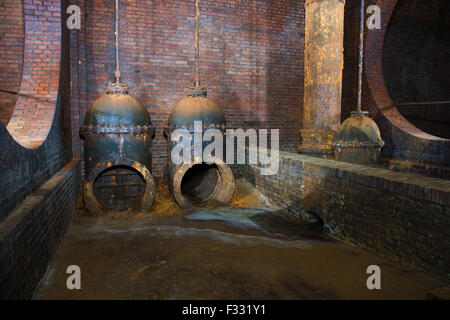 weit abgewinkelt Ansicht zwei stillgelegten rostiges Trinkwasser Absperrventil in einem unterirdischen Backstein Hall; Langfristige Exposition erschossen Stockfoto