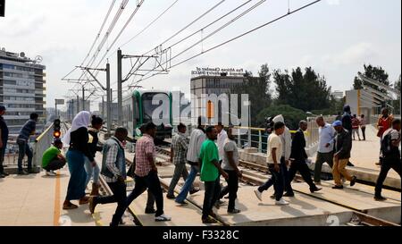 Addis Abeba, Äthiopien. 22. Sep, 2015. Menschen passieren eine Kreuzung einer Straßenbahn in Addis Abeba, Äthiopien, 22. September 2015. Äthiopien eröffnet des Landes und Sub-Sahara Afrikas erste Stadtbahn am 20. September die Addis Abeba Light Rail Transit (AA-LRT), gebaut von der China Railway Group (CREC). Der China Railway Engineering Corporation wird die ersten fünf Jahre in Betrieb und die Wartung des leichten Zuges, bevor der äthiopischen Railway Corporation übernimmt beteiligt sein. Foto: Marthe van der Wolf/Dpa/Alamy Live News Stockfoto