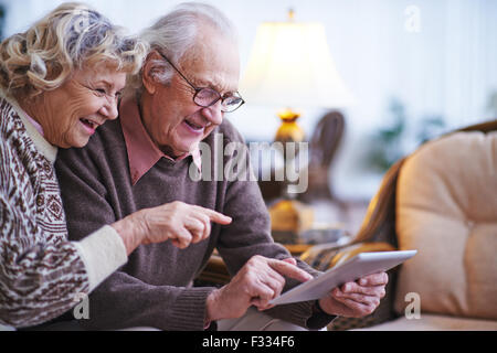 Gerne älteres Paar mit Touchpad zu Hause Stockfoto