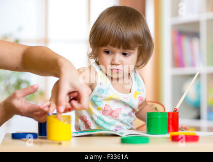 Lehrer und Kind zusammen im Kindergarten mit Pinsel und Wasserfarben malen Stockfoto