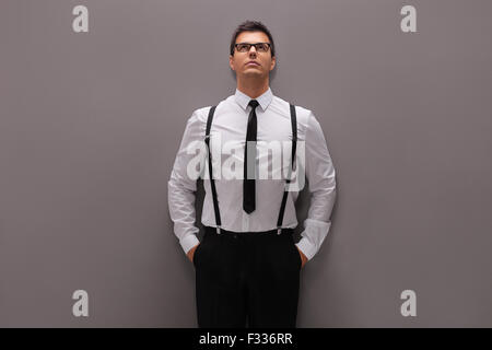 Zuversichtlich, junger Mann im eleganten Outfit eine graue Wand gelehnt und nachschlagen Stockfoto