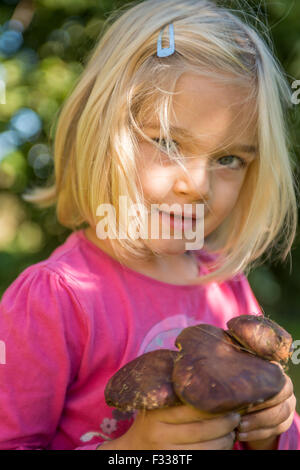 Porträt von Kind blondes Mädchen Abholung Pilze im Wald, machen Spaß, Sommer, Wald, Holz, Wald Stockfoto