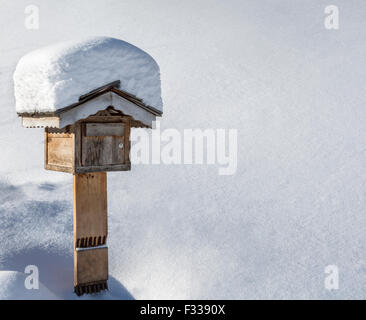 Hölzerne Postfach unter dem Schnee in einem Innenhof im Winter. Stockfoto