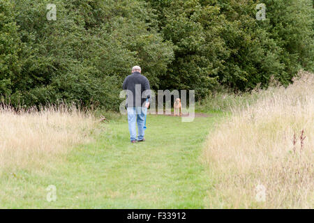 Mann, telefonieren mit Handy während Ballweitwurf mit Chuck-It Spielzeug für Hund in Landschaft in Bedford, Bedfordshire, England Stockfoto