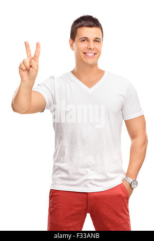 Vertikalen Schuss von einem jungen Mann, einen Frieden Geste der hand und schaut in die Kamera, die isoliert auf weißem Hintergrund Stockfoto