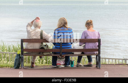 Drei Freunde sitzen auf einer Bank, Blick auf das Meer. Stockfoto