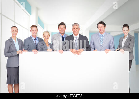 Zusammengesetztes Bild des Lächelns Business-Team hält Plakat Stockfoto