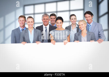 Zusammengesetztes Bild des Lächelns Business-Team hält Plakat Stockfoto