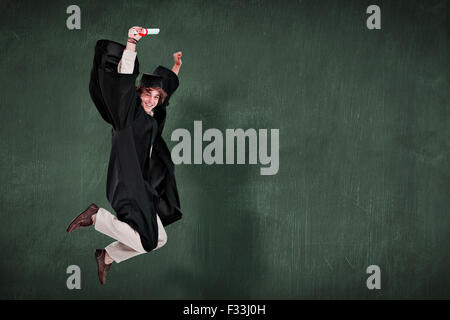 Zusammengesetztes Bild des glücklichen männlichen Studenten im Diplom Gewand springen Stockfoto