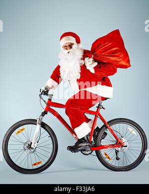 Weihnachtsmann mit rotem Sack, die mit Fahrrad Stockfoto