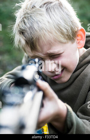 Porträt eines kleinen Jungen mit Luftgewehr schießen im Freien, Luftgewehr mit Zielfernrohr Stockfoto