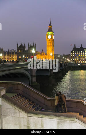ein paar küssen in der Abenddämmerung auf dem Damm mit Big Ben, der Palast des Westmintster und der Themse über London, England Stockfoto