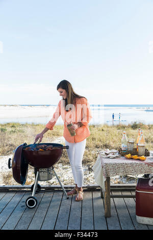 Frau am Strand grillen Stockfoto