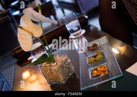 Cocktail-Erdnüsse, Oliven und Snacks auf eine dekorative, stimmungsvollen Candle-Light-Bar-Tisch Stockfoto