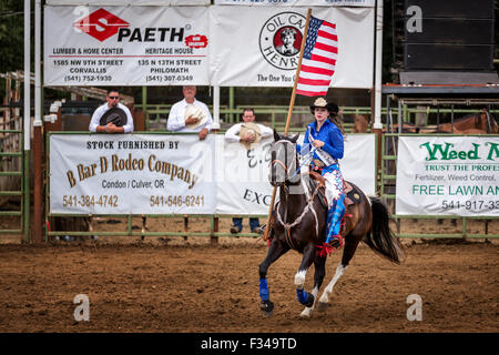 Cowgirl mit einer amerikanischen Flagge bei der Eröffnungsfeier eines Rodeo, Philomath Frolic & Rodeo, Oregon, USA Stockfoto