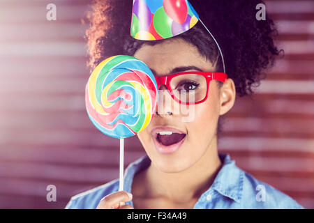 Überrascht junge Frau hält einen Lutscher gegen ihr Gesicht Stockfoto