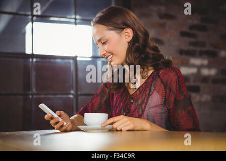 Lächelnde Brünette mit Kaffee und SMS Stockfoto