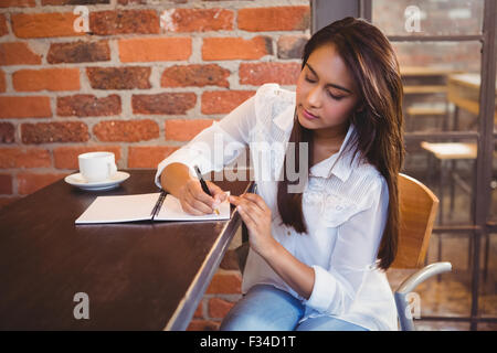 Lächelnde Geschäftsfrau mit Kaffee und planen ihre Woche Stockfoto