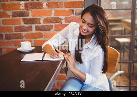 Lächelnde Geschäftsfrau mit Kaffee und planen ihre Woche Stockfoto