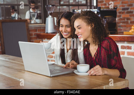 Glückliche Frauen Freunden Kaffee trinken und mit Blick auf laptop Stockfoto