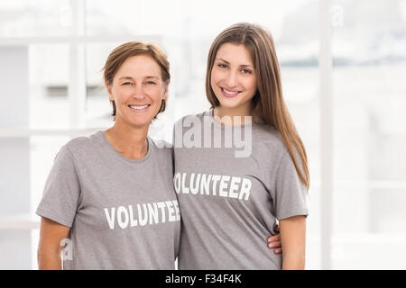 Lächelnd weibliche Probanden, die Arme umeinander Stockfoto